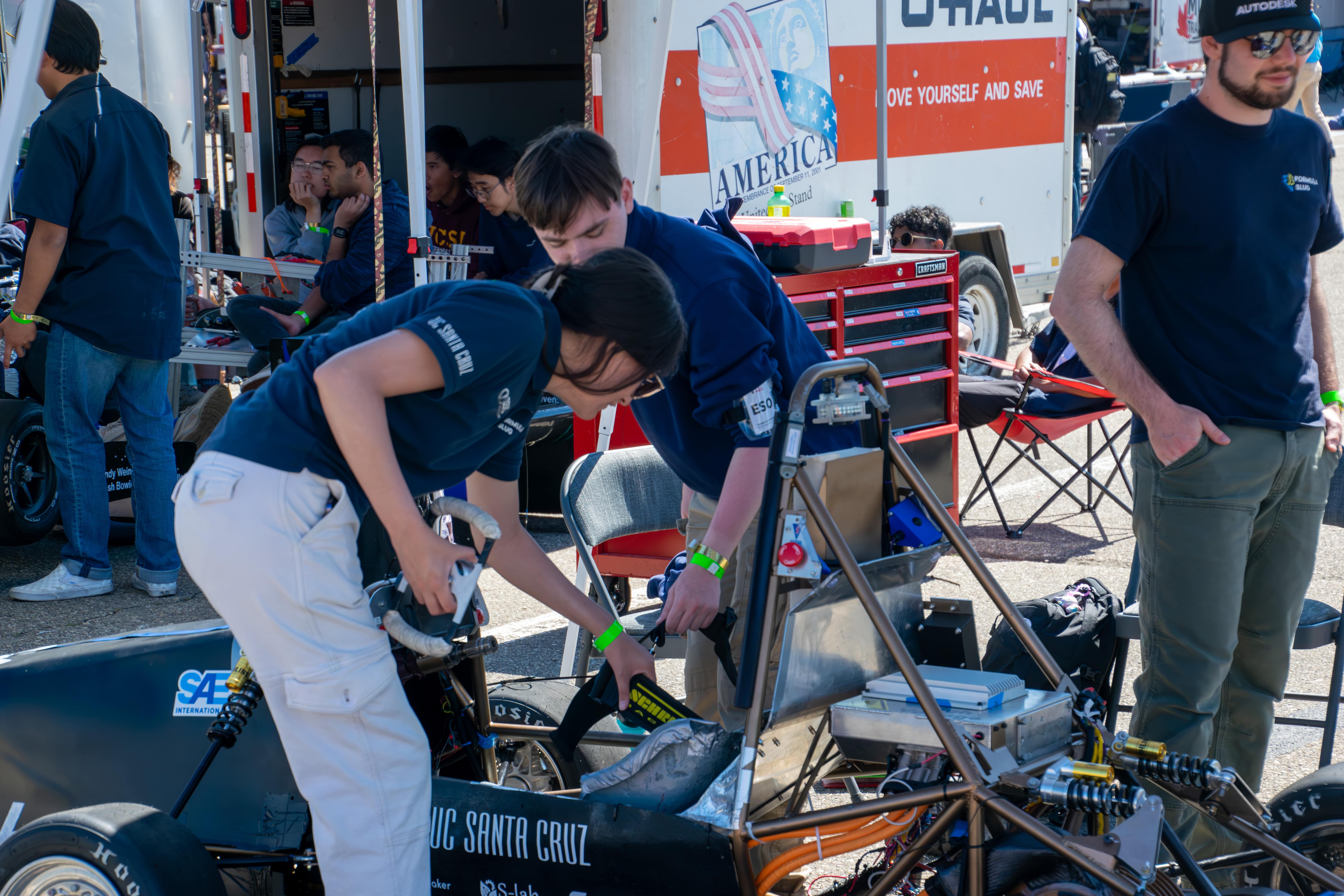 Two Team Members Work on the Car